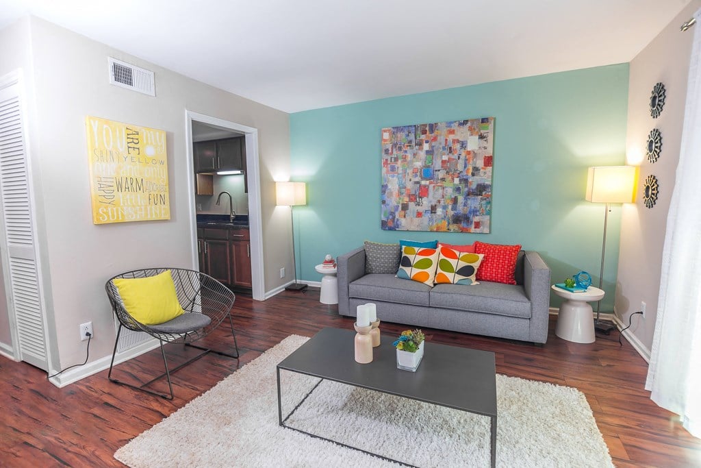 a living room with blue walls and a gray couch with colorful pillows